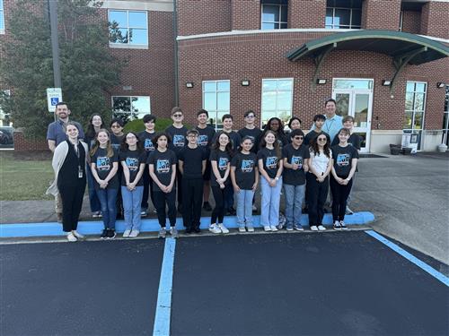21 Liberty Middle band members with principal and band directors standing in front of the Central Office